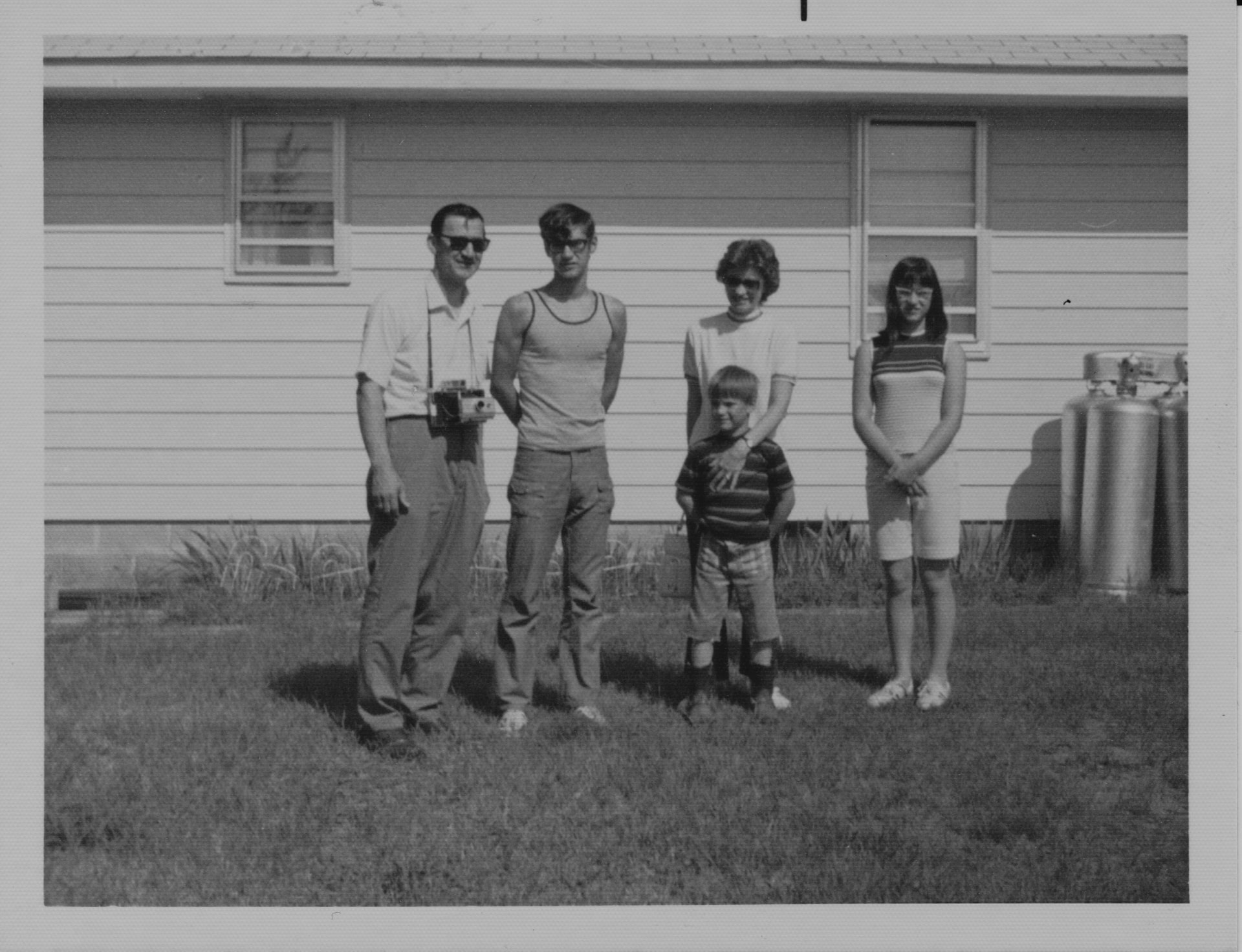 Leonard Ristow, Jr. with his camera at his side, standing with his family outside their home